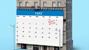 A calendar with the first day circled and labeled "RENT DUE", placed in front of an apartment building.