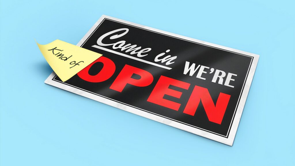 A sign reading "Come in, we're open" with a sticky-note reading "Kind of" placed before "Open".