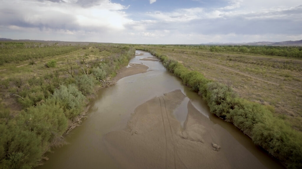 A dried-up river flanked by greenery.