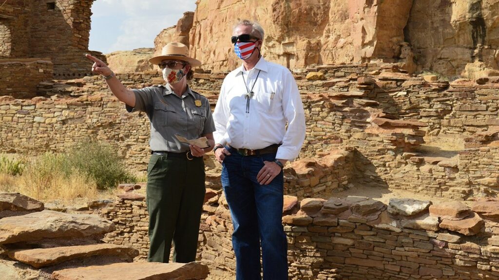 Two people stand with each other in a desert rocky area.