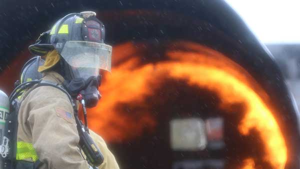 A firefighter combats a giant flame.