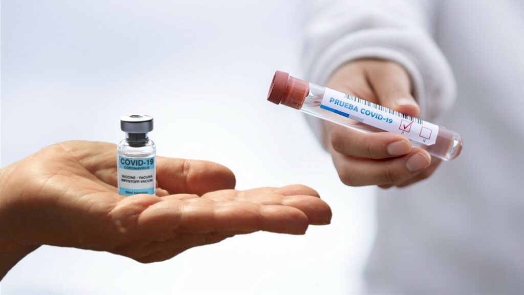 Two hands, both holding vials of COVID-19 vaccine.