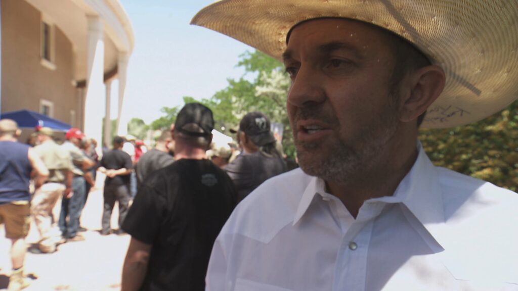 A man in a sunhat speaks outside of the Santa Fe Roundhouse.