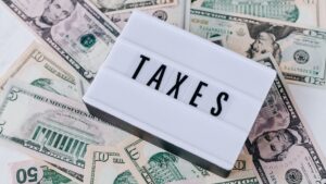 A sign reading "TAXES" lay over assorted dollar bills.
