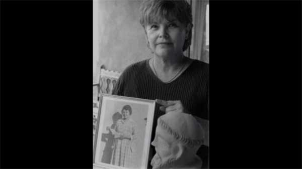 A person holds up an antique portrait.