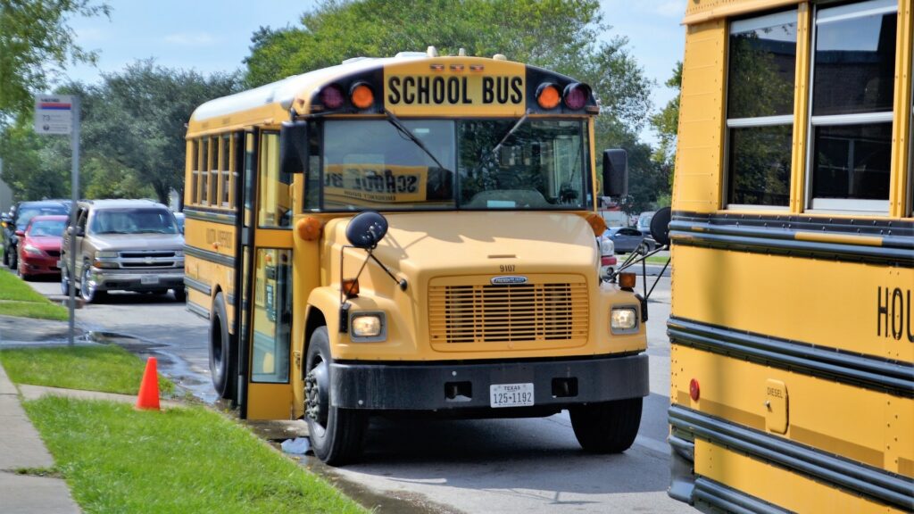 School buses park on a curb, waiting for students.