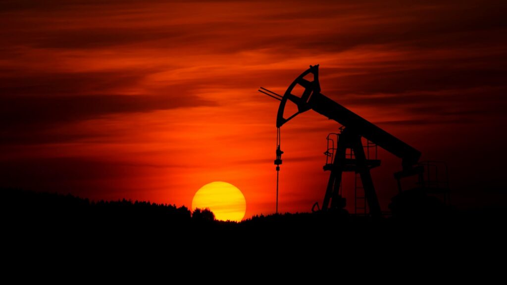 An oil drilling rig at work during sunset.