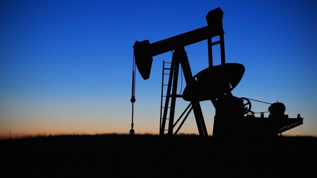 An oil drilling rig at work during sunrise.