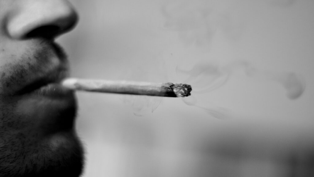 Close-up of a person smoking a cannabis joint.