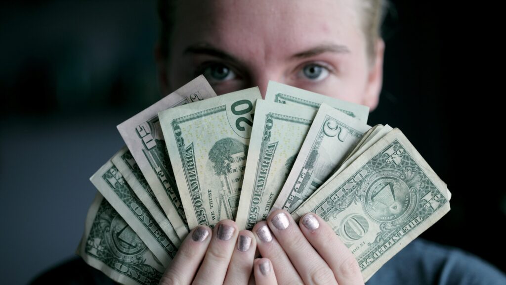 A person holds up several assorted U.S. dollar bills.