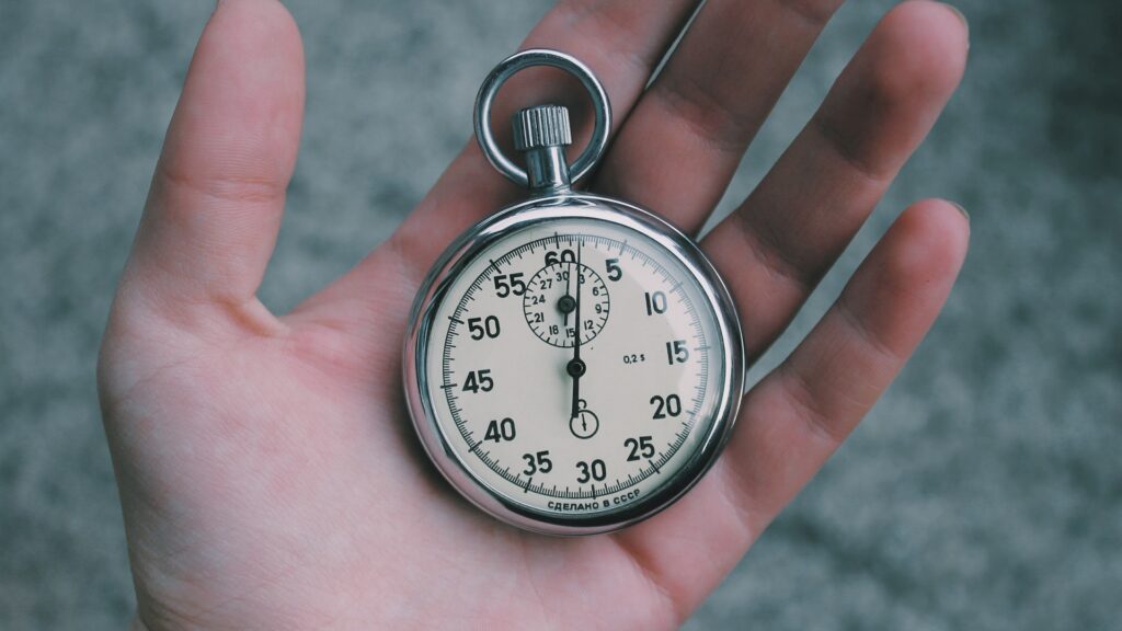 An open hand holding an antique stopwatch.