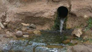 A tube within a rock releases water into a stream.