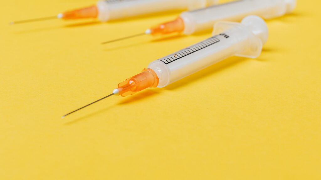 Close-up of a needle on a bright yellow backdrop.