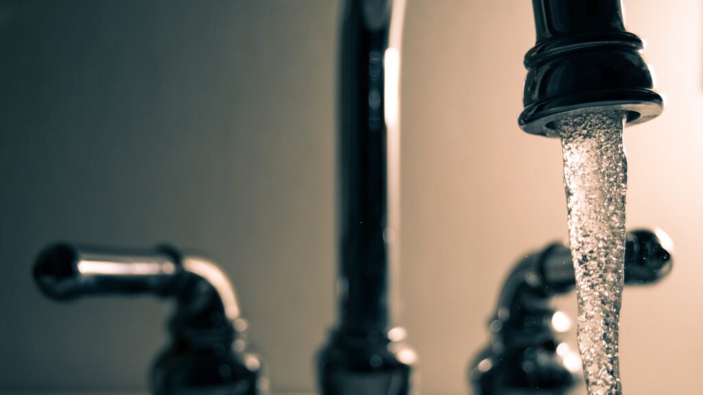 A faucet with a gush of water coming out the spout.