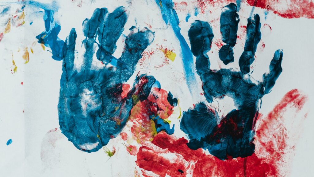 A canvas with assorted fingerpainted markings, including two handprints.