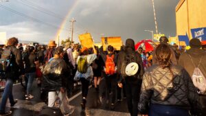 A rainbow comes out over demonstrators after a heavy downpour.