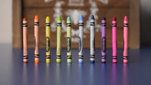 A line of 10 crayons of varying colors in a line.