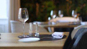 A restaurant table with wine glasses, plates, and silverware.