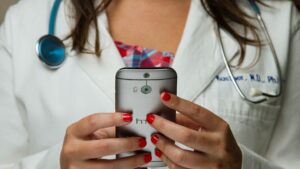 A closeup of a doctor holding a phone in their hands.