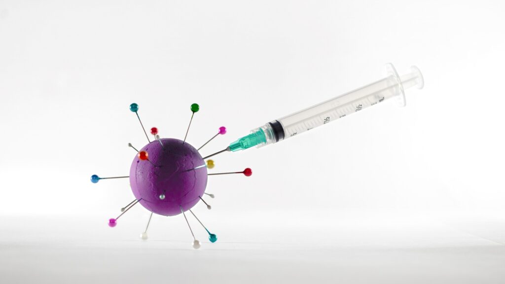 A syringe inserted into a representation of a coronavirus.