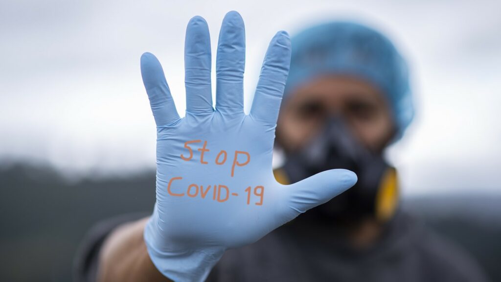 A medical professional wearing gloves that read "Stop Covid-19".