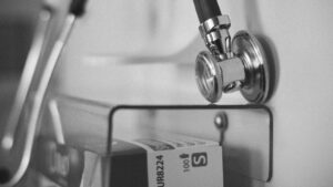 A black and white image of a stethoscope and other hospital items