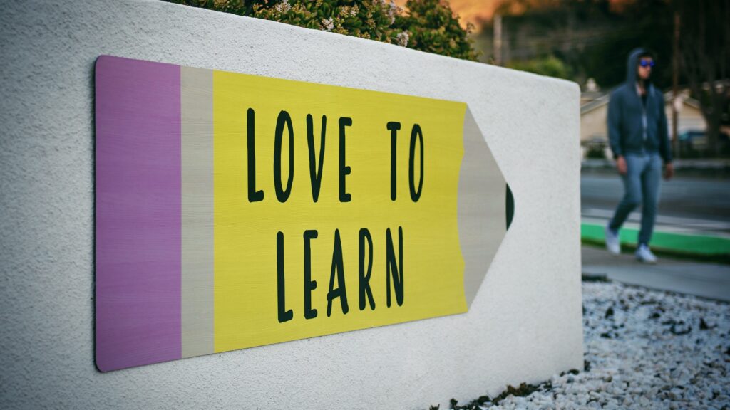 A sign with a pencil with "Love to Learn" printed inside.