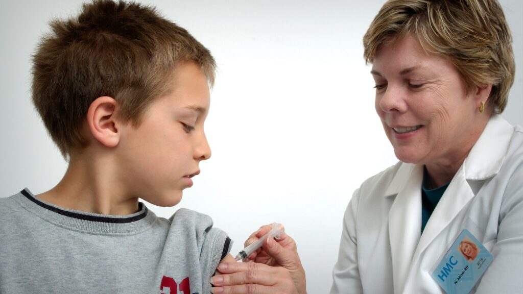 A nurse giving a child a vaccine shot in the arm