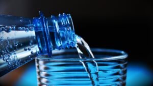 A blue water bottle pouring water into a glass