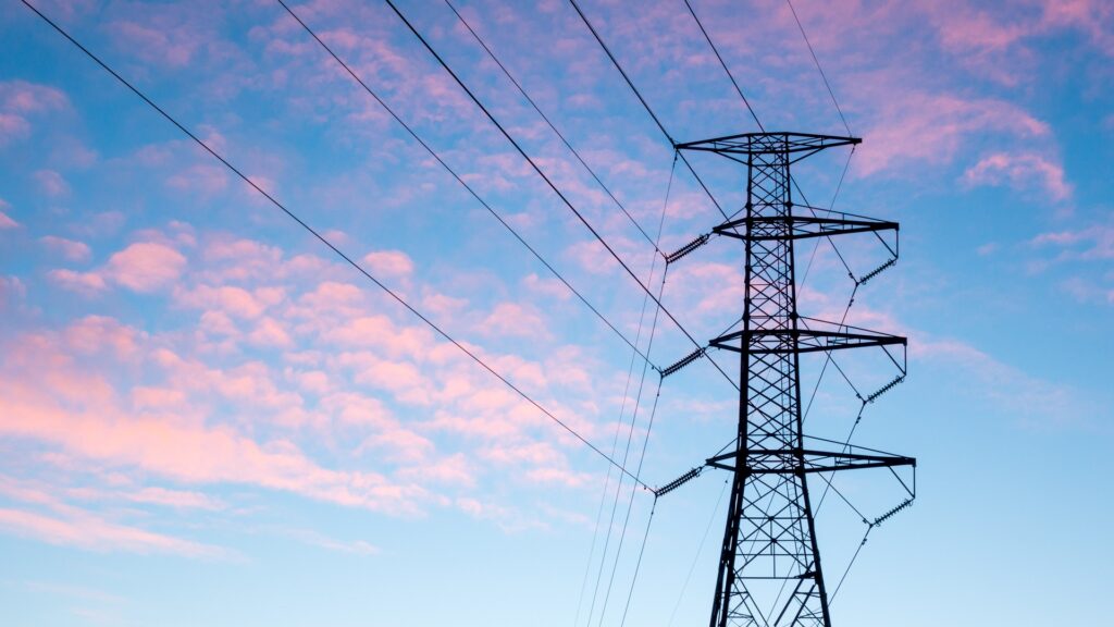 An electricity tower against a blue and purple sky.