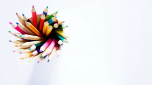 A cup of vibrant colored pencils against a white backdrop.