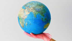A gloved hand holding up a globe of earth.
