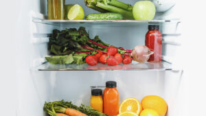 The inside of a fridge stocked with fruits and vegetables.