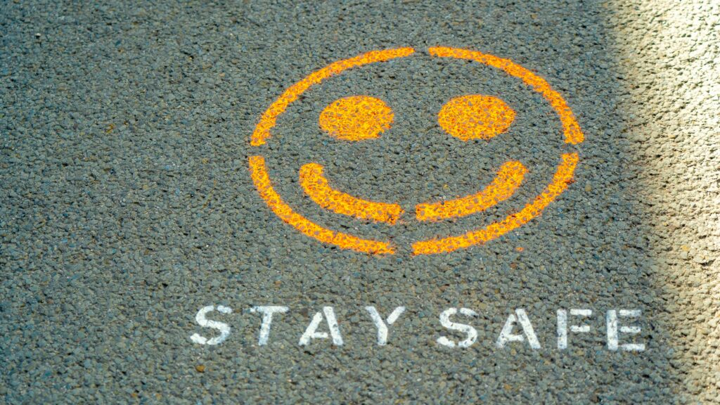 A smiley face and the words "stay safe" spray painted onto pavement.