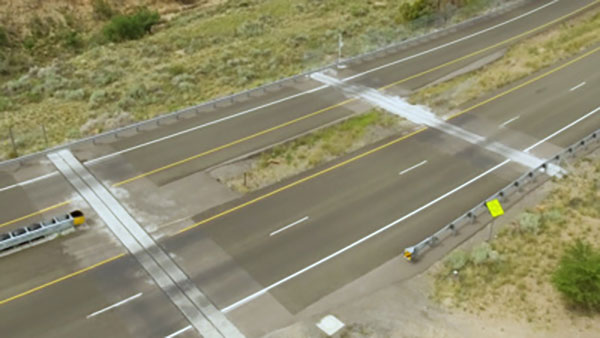 An overhead image of wildlife corridors running through two empty roads.