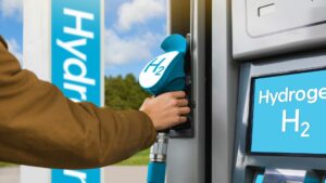 A person grabbing a pump at a hydrogen station that looks similar to a gas-station.