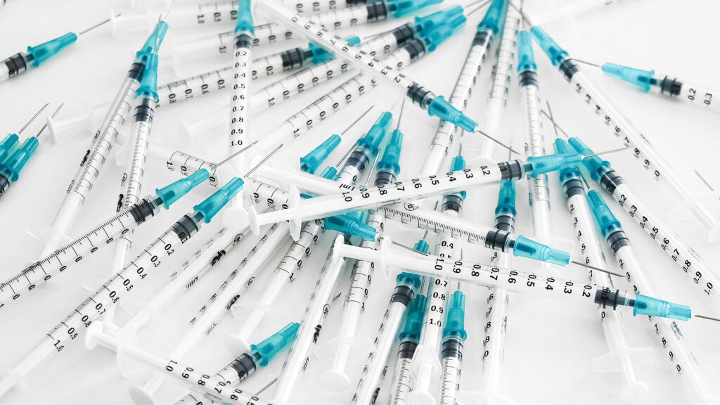 A pile of vaccine needles on a white background.