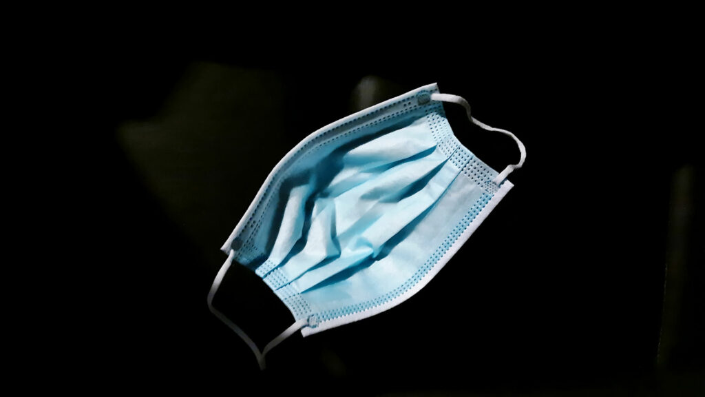 A disposable face mask on a black background.