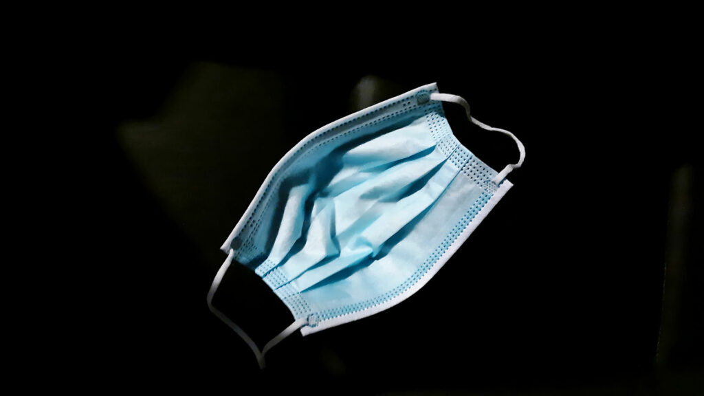 A disposable face mask on a black background.