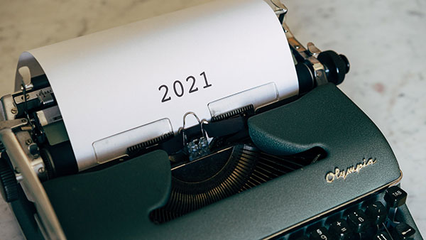 A green typewriter with 2021 typed onto a piece of paper.