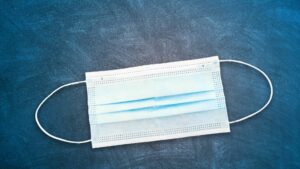 A disposable face mask on top of a blue background.