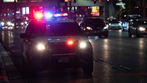 A police car with the lights on parked on a busy street at night.