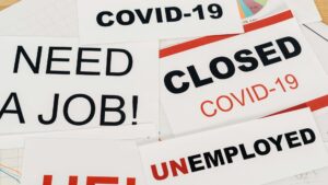 A pile of signs reading various things like "closed COVID-19", "unemployed", "need a job!"