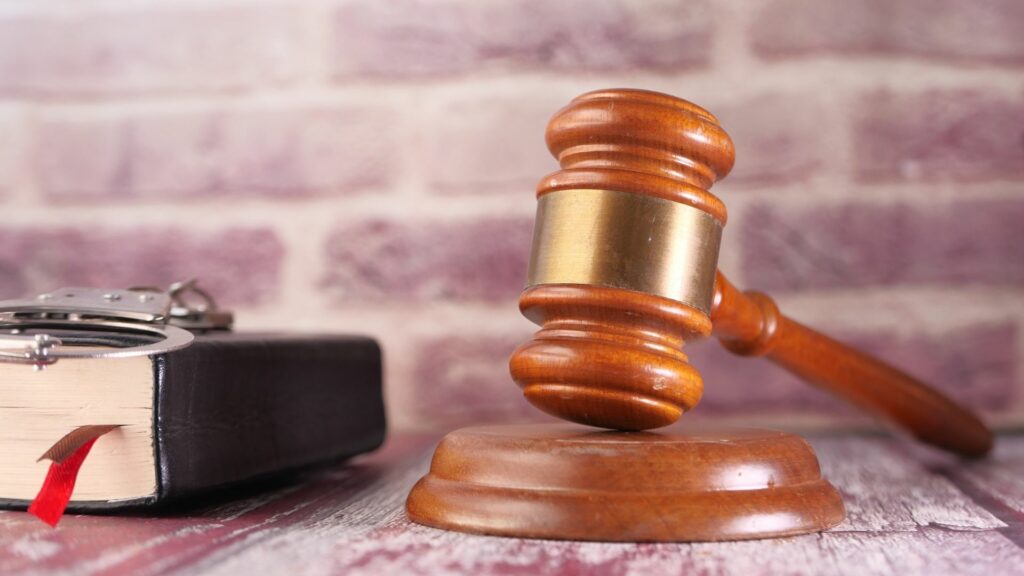 A bible, pair of handcuffs, and a gavel sitting on a table.