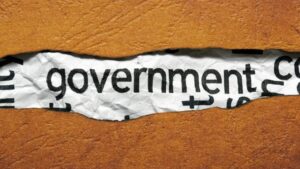 A ripped piece of brown paper sitting on top of another page revealing the world "government."