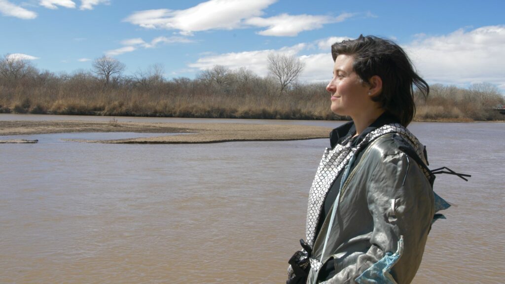 A person standing looking to left with the Rio Grande behind them.