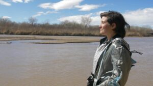 A person standing looking to left with the Rio Grande behind them.