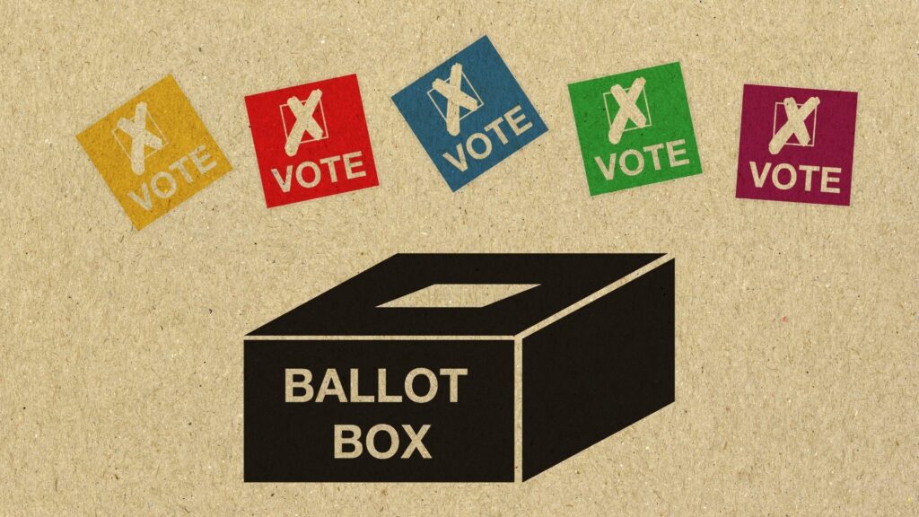 A graphic of a voting box with color full squares representing votes floating over top.