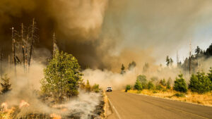 A car driving away from a wildfire.