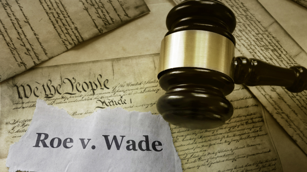 The declaration of Independence with a gavel and a piece of paper that reads "Roe v. Wade" sitting on top.